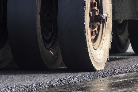 closeup wheel of roller compactor at asphalt road construction siteの写真素材