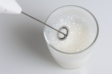 making foamy milk with milk frotherの写真素材