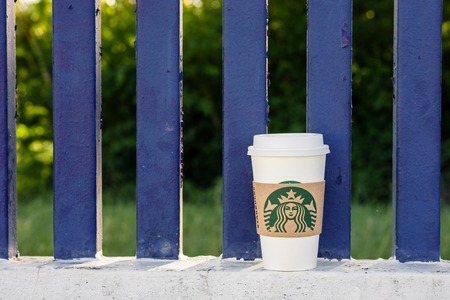 BANGKOK, THAILAND - MAY 22, 2015: White paper cup with Starbucks logo on fence. Starbucks is the world's largest coffee house with over 20,000 stores in 61 countries.のeditorial素材