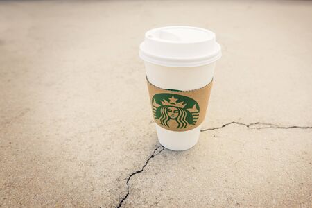 BANGKOK, THAILAND - MAY 22, 2015: White paper cup with Starbucks logo on cracking concrete. Starbucks is the world's largest coffee house with over 20,000 stores in 61 countries.のeditorial素材