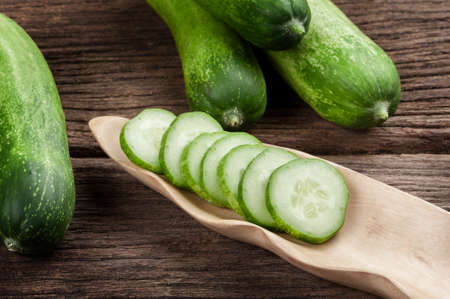 sliced fresh cucumbers in wooden bowlの写真素材