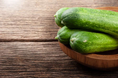 heap of fresh cucumbers in wooden bowlの写真素材