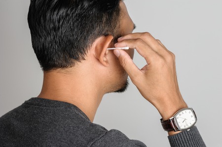 asian man cleans his ear with cotton swab