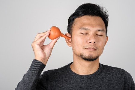 Asian man using soft bulb washer to clean his earの写真素材