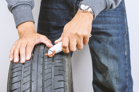 The man repairing flat car tire with repair kit, Tire plug repair kit for tubeless tires.の写真素材
