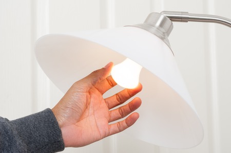 closeup hand changing an electric light bulbの写真素材
