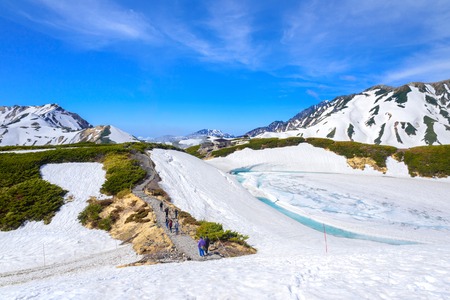 TATEYAMA, JAPAN - MAY 17, 2016: Travelers at Murodo with Tateyama Mountain Range in the background. Murodo is the highest point along the Tateyama Kurobe Alpine Route.のeditorial素材