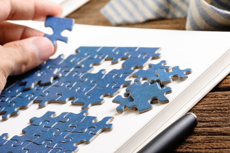 playing blue jigsaw puzzle game on wooden tableの写真素材