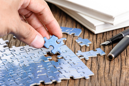 playing blue jigsaw puzzle game on wooden tableの写真素材