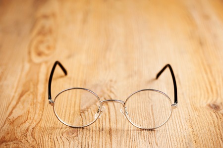 closeup round frame style of eyeglasses on wooden desk, shallow depth of fieldの写真素材