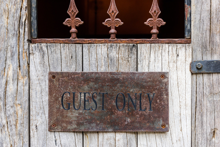 closeup the word GUEST ONLY painted on old rusty steel on old wooden doorの写真素材