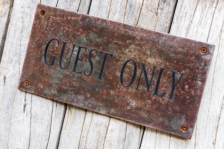 closeup the word GUEST ONLY painted on old rusty steel on old wooden doorの写真素材