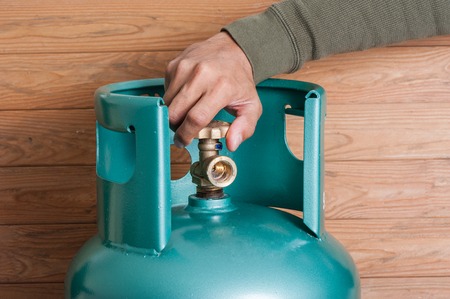 Closeup man's hand operating valve of LPG cylinder for cookingの写真素材