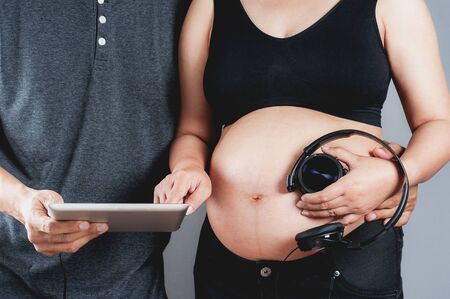 Pregnant woman and her husband selecting the songs for babyの写真素材