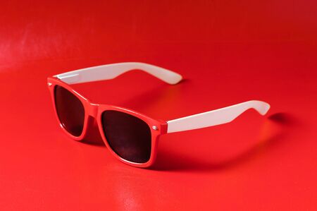 woman accessory, closeup red plastic sunglasses over red backgroundの写真素材