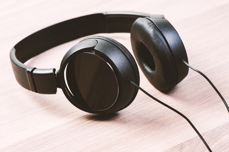 wired black headphone isolated on wooden backgroundの写真素材