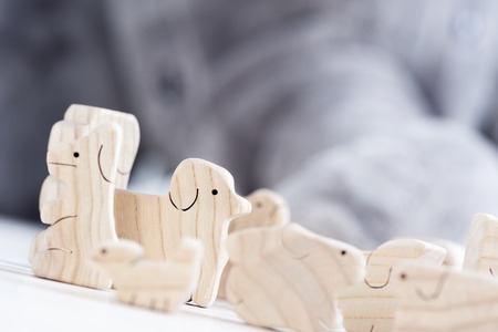 cute wooden toy animals on white wood plank with giant elephant doll in the backgroundの写真素材