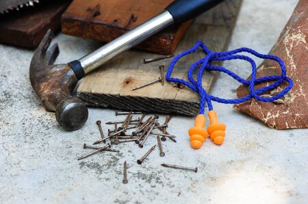 Orange reusable ear plugs in construction site, personal safety equipment concept. Outdoor shooting...
