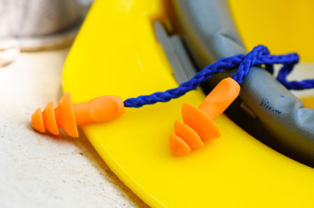 Orange reusable ear plugs in construction site, personal safety equipment concept. Outdoor shooting and shallow depth of field.の写真素材