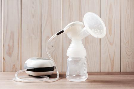 Breast pump and blank baby bottle on wood backgroundの写真素材