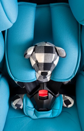 teddy bear in blue child safety seat, seat designed specifically to protect children from injury or death during collisions.の写真素材