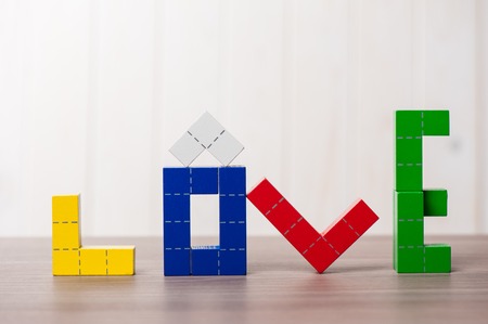 colorful wooden puzzle blocks toy, wooden construction blocks with geometric shapes. the word love