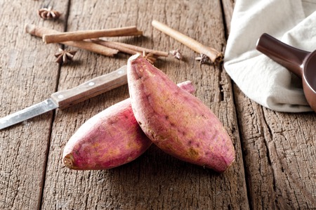 raw sweet potato over old wood background の写真素材