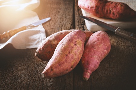 raw sweet potato over old wood background の写真素材
