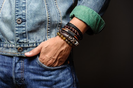 The man in jean jacket wearing bracelets, casual style of men accessories. Shallow depth of field.