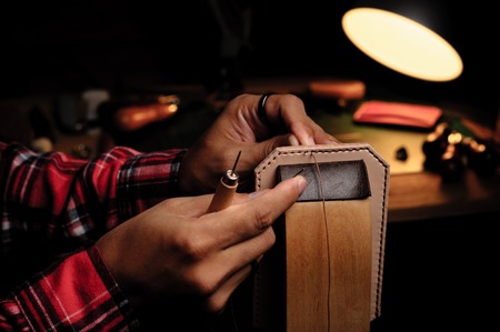 Sewing the vegetable tanned leather by hand. Leather and the craft tools.の写真素材