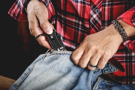 the man distressing jeans with folding knife.の写真素材