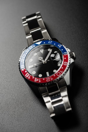 closeup luxury wristwatch for men with black dial blue-red bezel and stainless steel bracelet.の写真素材