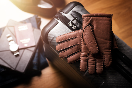 Pair of men's brown leather gloves and other men's accessories on the luggage.の写真素材
