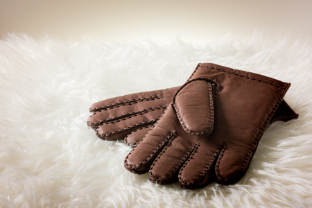 Pair of men's brown leather gloves with accent stitching in dark brown over white fur.の写真素材