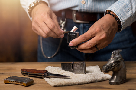 The man preparing to refill his chrome lighter.の写真素材