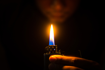 The man holding Brushed chrome lighter with windproof in the dark.の写真素材