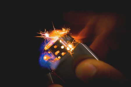 abstract brushed chrome lighter with windproof sparking in the dark.の写真素材