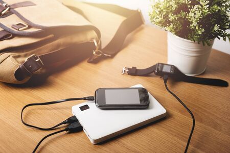 Charging the empty battery smartphone with white power bank. Shallow depth of field.