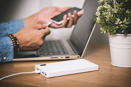 Charging the empty battery smartphone with white power bank. Shallow depth of field.の写真素材