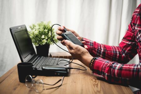 Black power bank connected with USB cable. Charging smartphone with power bank. Shallow depth of field focused on power bank display.の写真素材