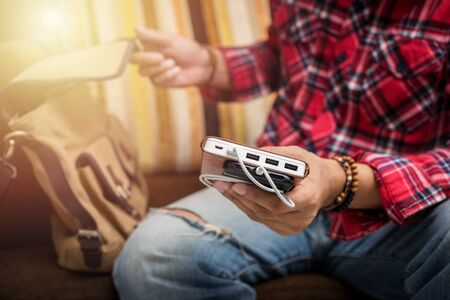 the man in red shirt charging smartphone with white power bank.