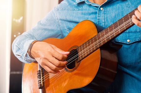 closeup man's hand playing his old classical guitar.