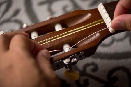 Restring classical guitar concept. The man restring his classical guitar.の写真素材