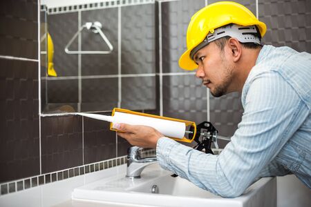 The man applying silicone sealant. The man fixing home.の写真素材