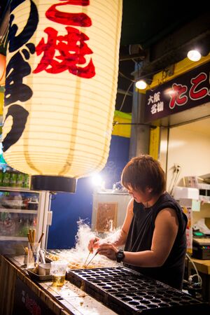 OSAKA, JAPAN - MAY 20, 2016: A Japanese man grills Takoyaki in Dotonbori, Osaka, Japan. Takoyaki is a famous Japanese street food in Japan.のeditorial素材