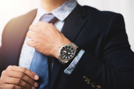 closeup luxury men watch with black dial and stainless steel bracelet on wrist of man.の写真素材