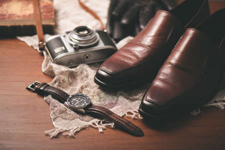 Men accessories on wooden desk. Closeup at luxury men watch with black dial and leather strap.