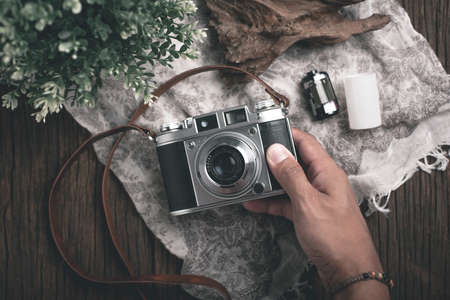 Photographer holding vintage camera in his hand over the desktop.