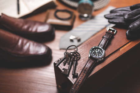 Men accessories on wooden desk. Closeup at luxury men watch with black dial and leather strap.の写真素材