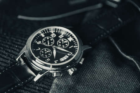 Closeup at luxury men wristwatch with black dial and leather strap.